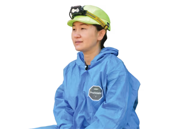 person with hardhat on and blue jumpsuit looking into the distance